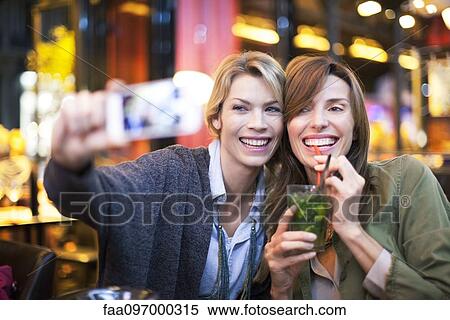 Stock Photography - Women in bar taking self-portrait with photophone. Fotosearch