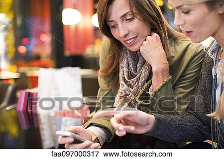 Women looking down at cell phone together View Large Photo Image Stock Photo - Women looking down at cell phone together. Fotosearch