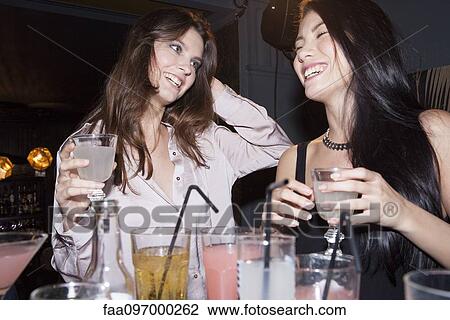 Stock Image - Women sharing laughs in nightclub. Fotosearch