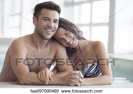 Stock Image - Young couple in pool together, portrait. Fotosearch