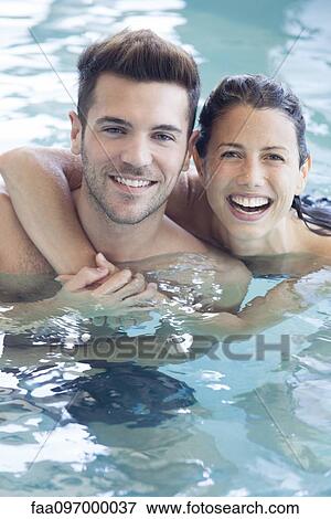 Stock Photo - Young couple in pool together, portrait. Fotosearch