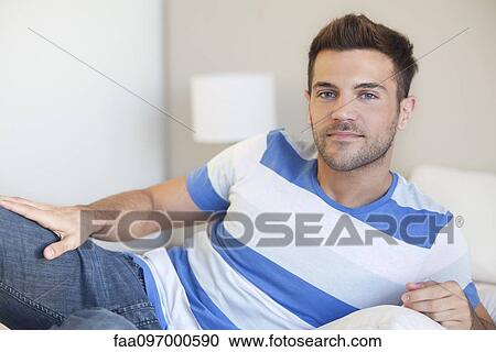 Stock Image - Young man reclining on bed. Fotosearch