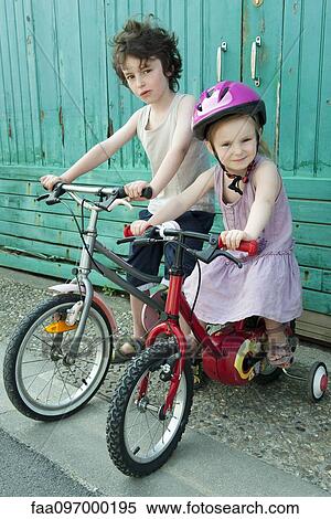 Stock Photography - Young siblings sitting together on bicycles. Fotosearch