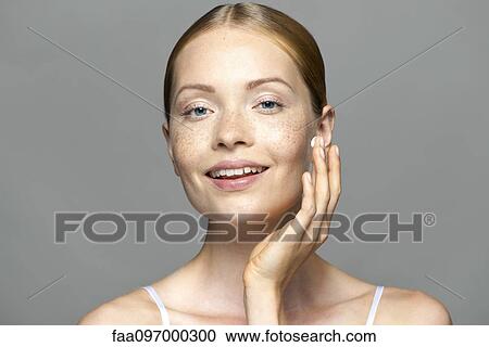 Stock Image - Young woman applying moisturizer to face. Fotosearch