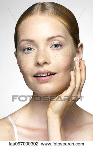 Stock Image - Young woman applying moisturizer to face. Fotosearch