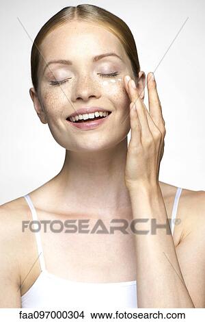 Picture - Young woman applying undereye cream. Fotosearch