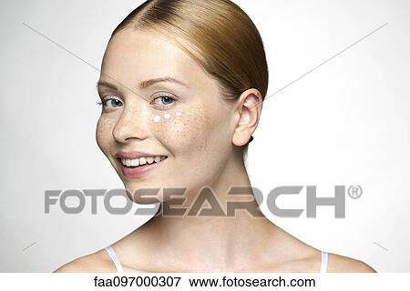 Stock Photo - Young woman applying undereye cream. Fotosearch
