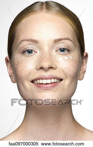 Stock Photography - Young woman applying undereye cream. Fotosearch