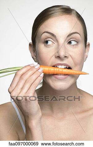 Young woman biting into carrot View Large Photo Image Stock Photo - Young woman biting into carrot. Fotosearch