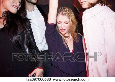 Young woman dancing with friends at night club View Large Photo Image Stock Photograph - Young woman dancing with friends at night club. Fotosearch