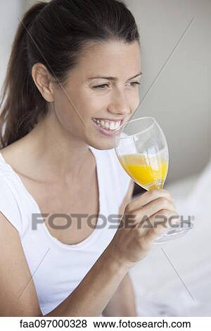Stock Photo - Young woman drinking glass of orange juice. Fotosearch