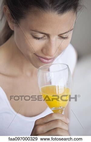 Stock Photo - Young woman drinking glass of orange juice. Fotosearch