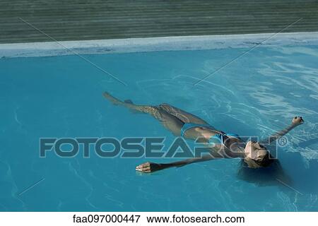 Stock Photo - Young woman floating in swimming pool. Fotosearch
