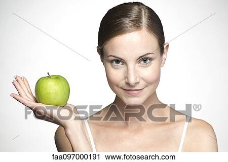 Young woman holding up green apple View Large Photo Image Stock Image - Young woman holding up green apple. Fotosearch