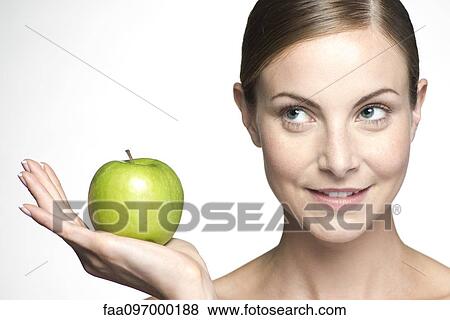 Stock Photo - Young woman holding up green apple. Fotosearch
