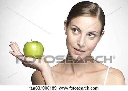 Stock Photo - Young woman holding up green apple. Fotosearch