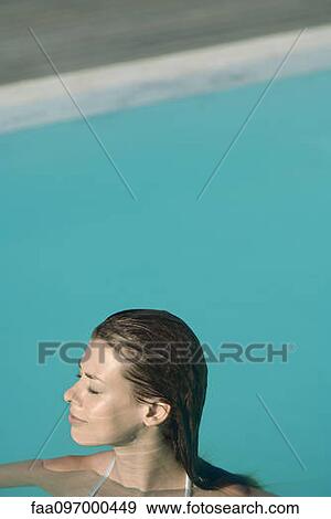 Stock Photo - Young woman in swimming pool, eyes closed. Fotosearch
