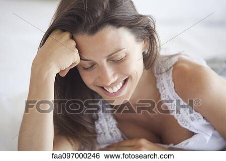 Stock Photograph - Young woman leaning on elbow, looking down, portrait. Fotosearch