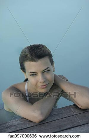 Young woman leaning on poolside, smiling View Large Photo Image Stock Photograph - Young woman leaning on poolside, smiling. Fotosearch
