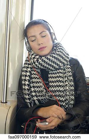 Young woman listening to music on subway train with eyes closed View Large Photo Image Stock Photo - Young woman listening to music on subway train with eyes closed. Fotosearch