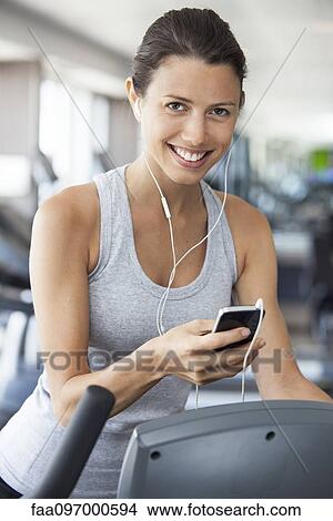 Young woman listening to music while using step climber at gym View Large Photo Image Picture - Young woman listening to music while using step climber at gym. Fotosearch