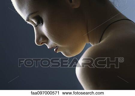 Stock Image - Young woman looking down, profile, close-up. Fotosearch