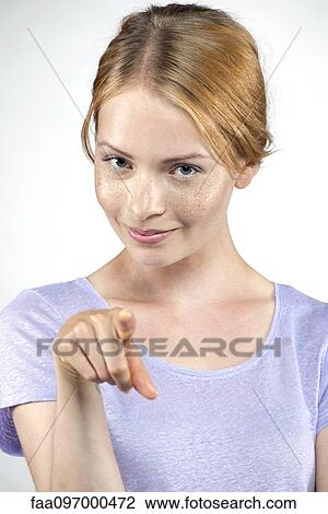 Stock Image - Young woman pointing at viewer. Fotosearch