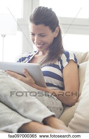 Stock Photography - Young woman relaxing at home using digital tablet. Fotosearch