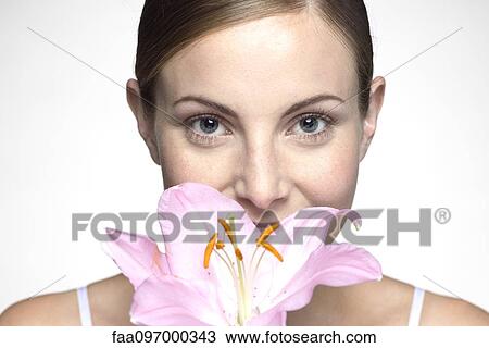 Stock Image - Young woman smelling orchid. Fotosearch