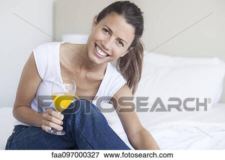 Stock Photo - Young woman starting her day with glass of orange juice. Fotosearch