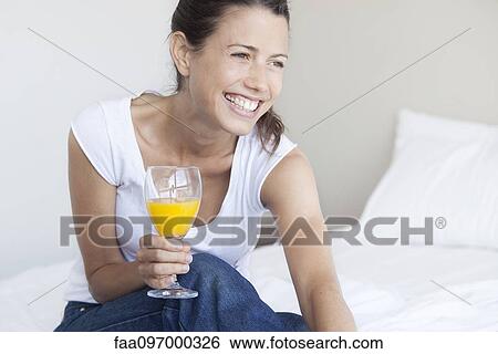 Young woman starting her day with glass of orange juice View Large Photo Image Stock Photograph - Young woman starting her day with glass of orange juice. Fotosearch