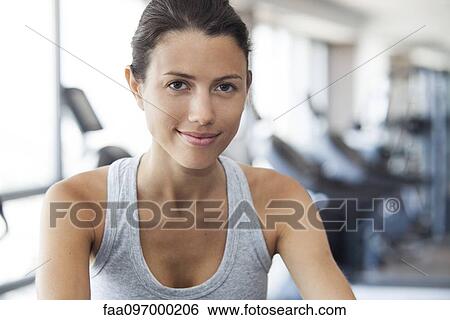 Stock Photograph - Young woman using exercise machine at gym. Fotosearch