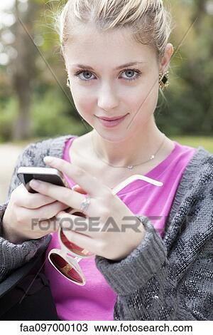 Stock Image - Young woman using smartphone. Fotosearch