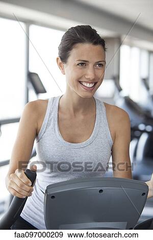 Stock Photo - Young woman using step climber at gym. Fotosearch