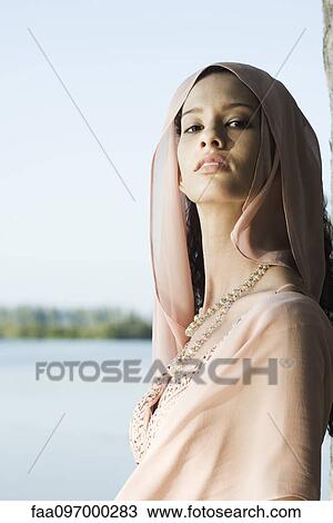 Stock Image - Young woman wearing head scarf, portrait. Fotosearch