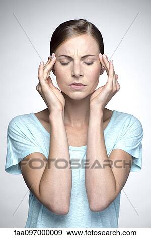 Stock Photo - Young woman with headache holding head. Fotosearch