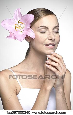 Stock Image - Young woman with orchid in hair. Fotosearch