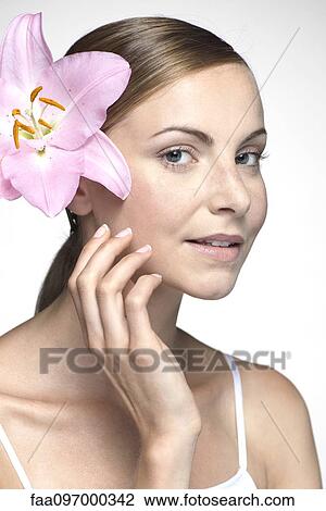 Stock Image - Young woman with orchid in hair. Fotosearch