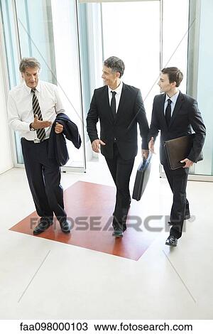Business associates chatting while entering office building together View Large Photo Image Stock Image - Business associates chatting while entering office building together. Fotosearch