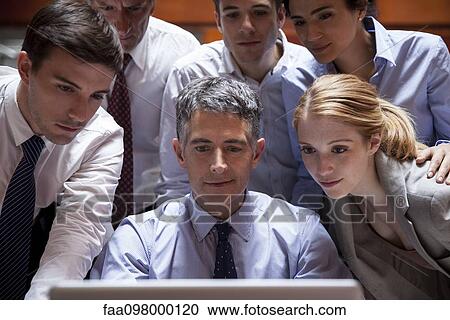 Business associates crowd around colleague looking over his shoulder at laptop computer View Large Photo Image Stock Image - Business associates crowd around colleague looking over his shoulder at laptop computer. Fotosearch