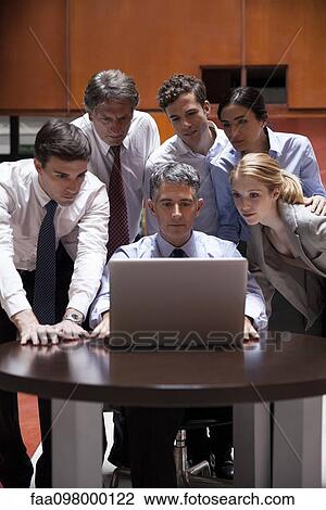 Business associates crowd around colleague looking over his shoulder at laptop computer View Large Photo Image Stock Image - Business associates crowd around colleague looking over his shoulder at laptop computer. Fotosearch