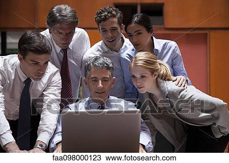 Business associates crowd around colleague looking over his shoulder at laptop computer View Large Photo Image Stock Image - Business associates crowd around colleague looking over his shoulder at laptop computer. Fotosearch