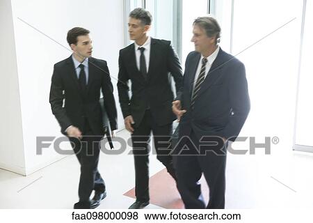 Stock Photo - Business associates entering office building together. Fotosearch