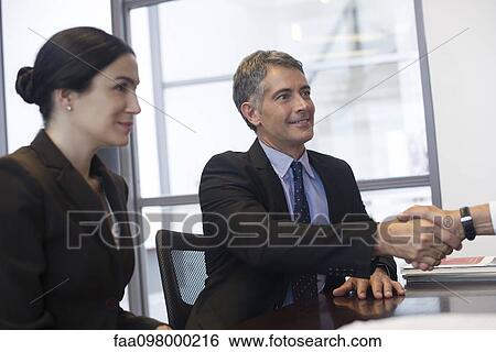 Business meeting, businessman shaking hands with out-of-frame associate View Large Photo Image Stock Photograph - Business meeting, businessman shaking hands with out-of-frame associate. Fotosearch