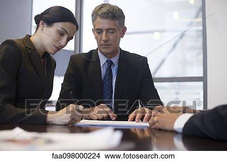 Business meeting, businesswoman signing document while associates observe View Large Photo Image Picture - Business meeting, businesswoman signing document while associates observe. Fotosearch