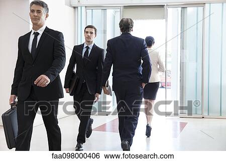 Stock Photograph - Business professionals passing through office lobby. Fotosearch