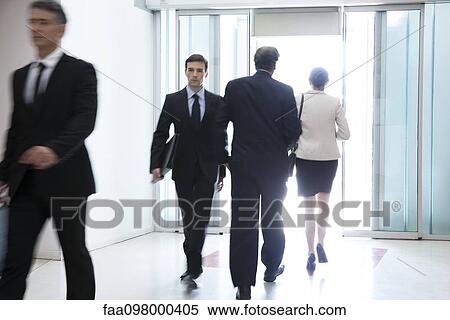 Stock Photography - Business professionals passing through office building lobby. Fotosearch