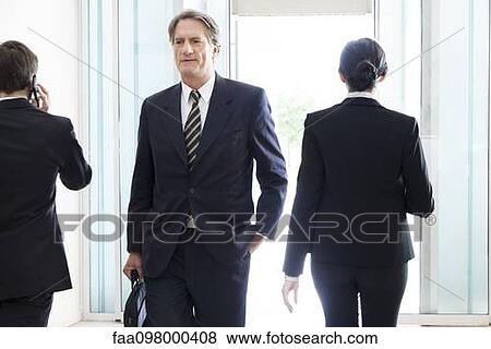 Businessman entering office building lobby View Large Photo Image Stock Photo - Businessman entering office building lobby. Fotosearch