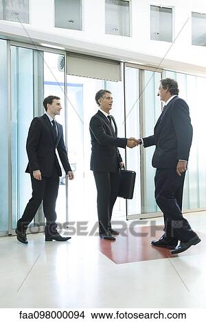 Picture - Businessman meeting associates in office lobby. Fotosearch