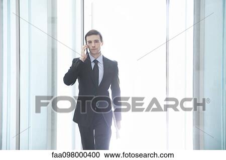 Stock Image - Businessman on the move using cell phone. Fotosearch